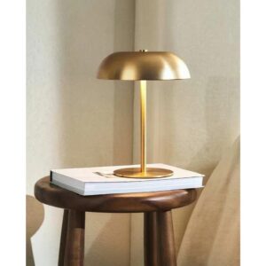 Złota lampa stołowa na drewnianym stoliku